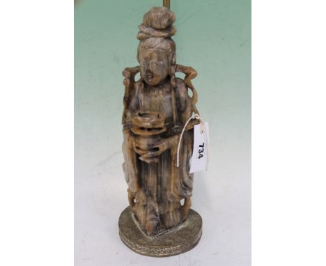 A CHINESE CARVED SOAPSTONE FIGURE OF A STANDING DEITY MOUNTED AS A LAMP.