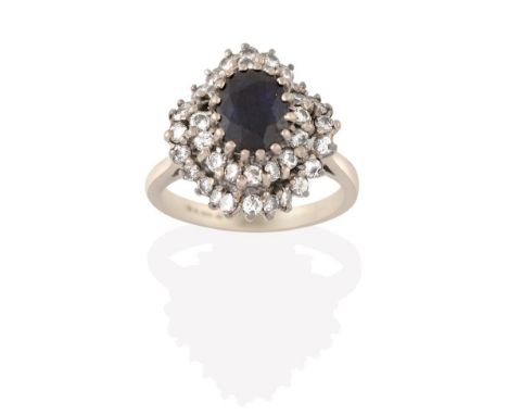 An 18 Carat White Gold Sapphire and Diamond Cluster Ring, the oval cut sapphire within a double undulating border of round br