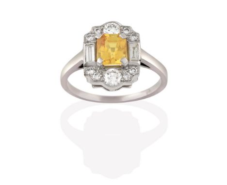 A Yellow Sapphire and Diamond Cluster Ring, the emerald-cut yellow sapphire within a border of baguette cut and round brillia