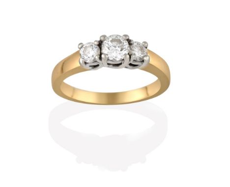 A Diamond Three Stone Ring, the graduated round brilliant cut diamonds in white claw settings, to a yellow tapered shoulder p