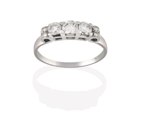 A Diamond Three Stone Ring, the graduated round brilliant cut diamonds in white claw settings, to scroll shoulders inset with