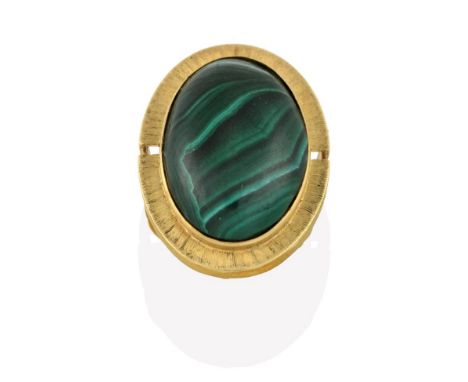 A Malachite Ring, the oval cabochon malachite in a yellow rubbed over setting to a further textured border, to a double row p