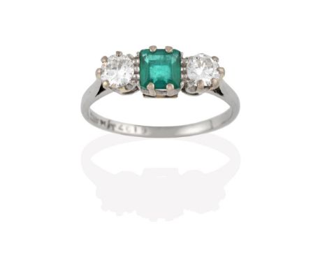 An Emerald and Diamond Three Stone Ring, the central step cut emerald flanked by round brilliant cut diamonds, in white claw 