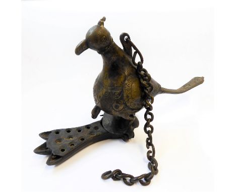 An antique Indian brass oil lamp formed as a bird perched on a pin hinged trefoil shaped base. H 15 cms x W 26 cms