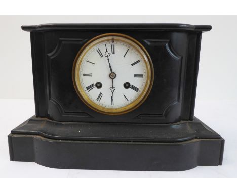 A late 19th century black slate eight-day mantle clock: white dial with Roman numerals and the brass movement striking on a b