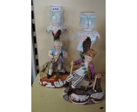 A pair of late 19th century continental porcelain figural candlesticksModelled in the form of a boy playing a musical instrum