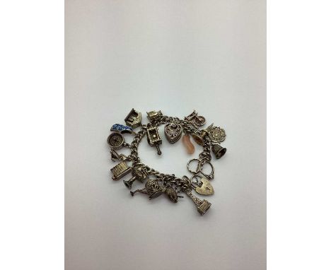 A Curb Link Charm Bracelet, to heart shape padlock style clasp, suspending numerous assorted novelty charm pendants, includin