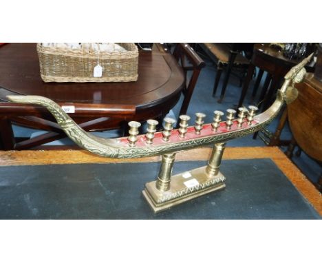 A BRASS TEMPLE LAMP in the form of a long boat, fitted nine candleholders