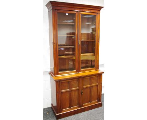 A mahogany bookcase, ogee cornice over two glazed doors enclosing adjustable shelving to top, two panel door cupboard, plinth