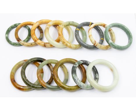 A collection of fourteen jade/ hardstone bangles in varying shapes, sizes and colours including grey, brown, green, etc, main