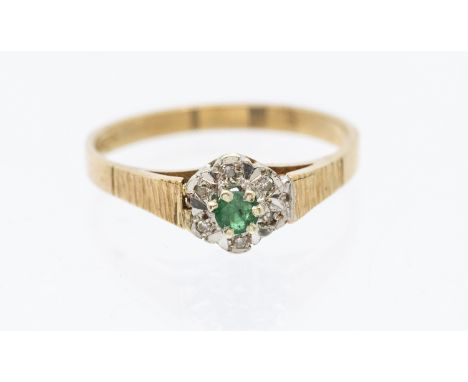 An emerald and diamond 9ct gold cluster ring with box - set to the center with a round emerald within a border of illusion se