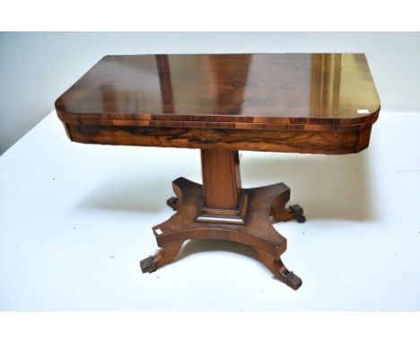 A 19th century rosewood folding card table with splayed legs and brass paw feet.