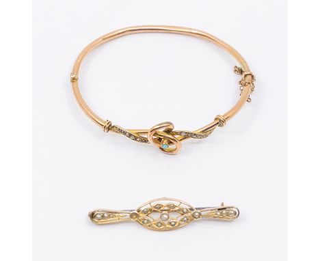 An early 20th Century 9ct rose gold turquoise and seed pearl hinged bangle comprising a gold knot set with a small turquoise 