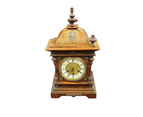 An early 20th century Junghans wooden cased bracket clock, with carved detail, metal mounted areas and finials to top (one mi