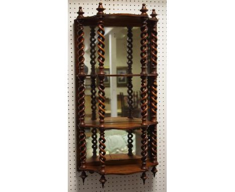 A Victorian serpentine mirror back three tier wall shelf, turned finials, helical twist supports. 76cm high x 37cm wide.