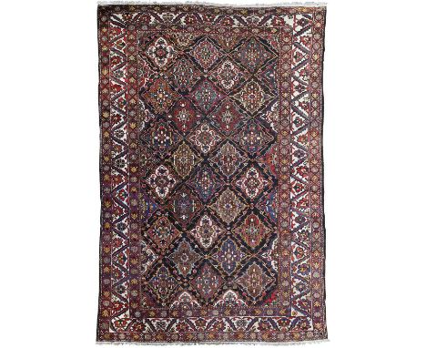 BAKHTIARI CARPET  NORTHWEST PERSIA, 20TH CENTURY  the dark indigo field with allover polychrome lozenge lattice pattern, with