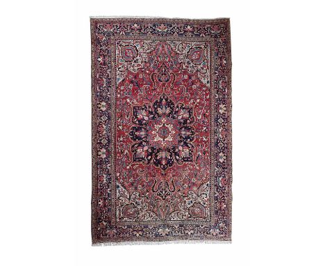 HERIZ CARPET  NORTHWEST PERSIA, LATE 20TH CENTURY  the red field with indigo medallion suspending pendants, cream spandrels, 