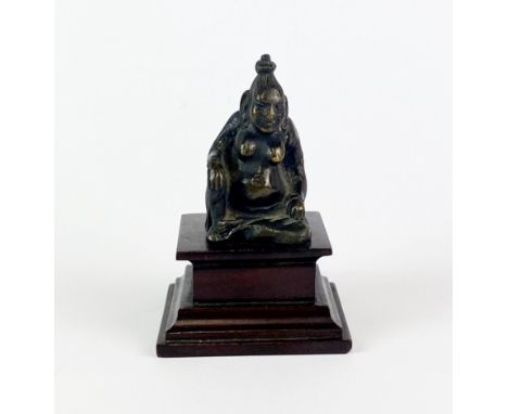 A small Eastern bronze figure of a seated deity on a later wooden plinth, H. 9.5cm.