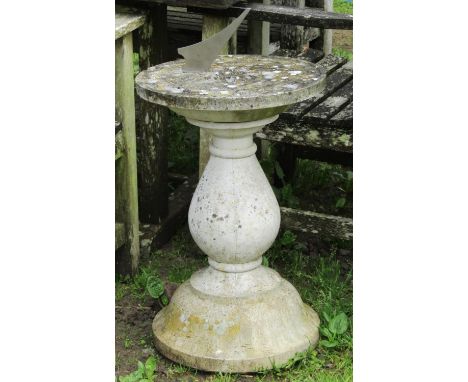 A weathered cast composition stone two sectional sundial of circular form, raised on a baluster pedestal with combined flared