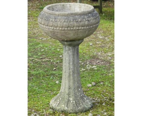 A weathered cast composition stone planter, the squat circular bowl with repeating bead bands raised on a fluted pedestal wit