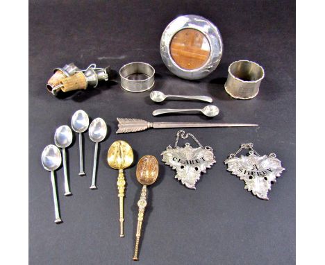 A selection of silver ware to include two napkin rings, two drinks labels, a small photo frame, two bottle spouts an arrow sk