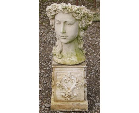 A weathered cast composition stone novelty female head planter raised on a low associated square pedestal with scrolling acan