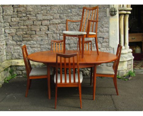 A G Plan teak extending dining table, circular when closed, incorporating under-leaf, raised on turned supports, together wit