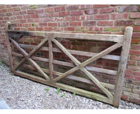A weathered soft wood five bar x framed field/entrance gate with chamfered detail and through jointed construction, 280 cm lo
