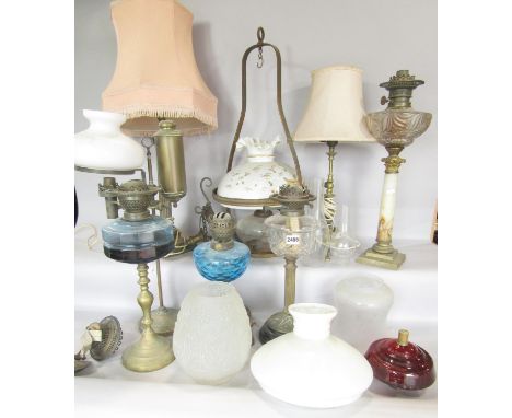 A brass Corinthian column, table lamp, a brass adjustable students lamp, four oil lamp bases a selection of shades and chimne