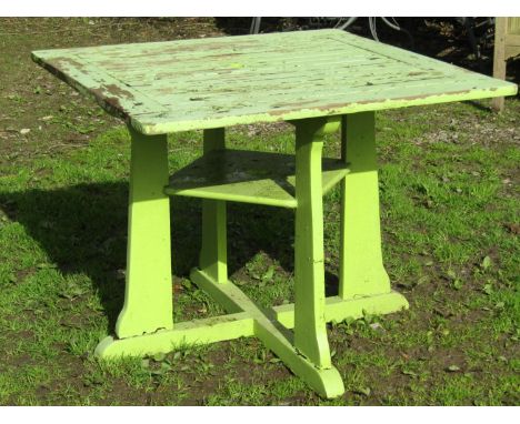 An Arts &amp; Crafts style light green painted and weathered teak garden table, the square slatted panelled top raised on sha