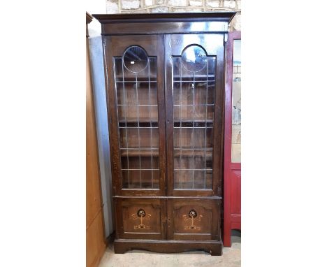 An Edwardian oak library bookcase enclosed by two leaded light doors over two panelled doors 100 cm wide 