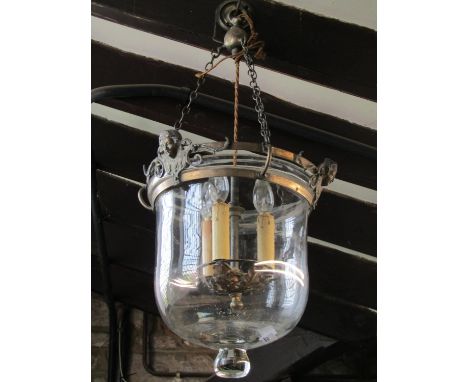 A vintage pendant light with glass dome shade and metal fittings with face mask detail