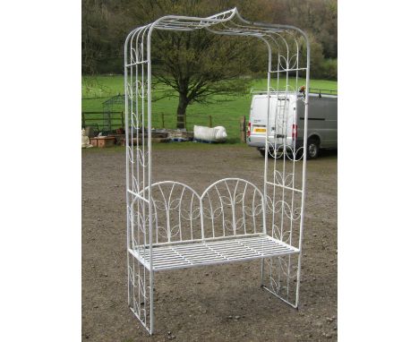 A cream painted light steel sectional garden arbour, with repeating open leaf patterned design and enclosing a two seat strap