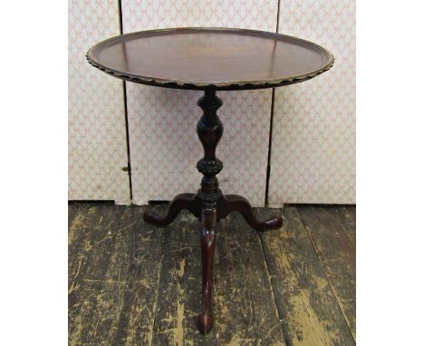 A Georgian style mahogany occasional table, the circular dished top set within a shaped outline, raised on a turned and decor