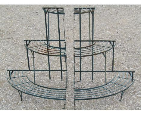 A pair of green painted light steel corner plant stands on three graduated bow fronted tiers, 75 cm high x 60 cm deep 