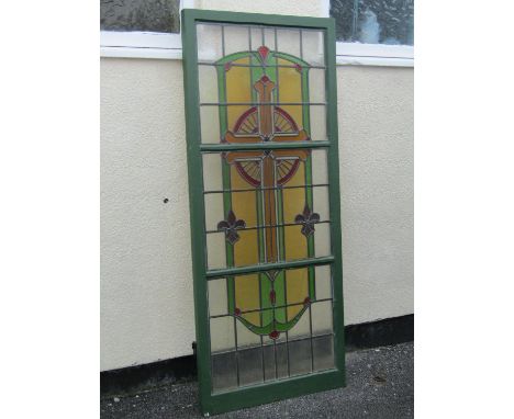 A reclaimed early 20th century wooden framed casement window enclosing stained leaded light panels forming a crucifix 71 cm w