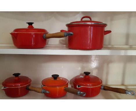 A collection of four cast iron saucepans, each with a lid, together with a further lighter casserole and cover 