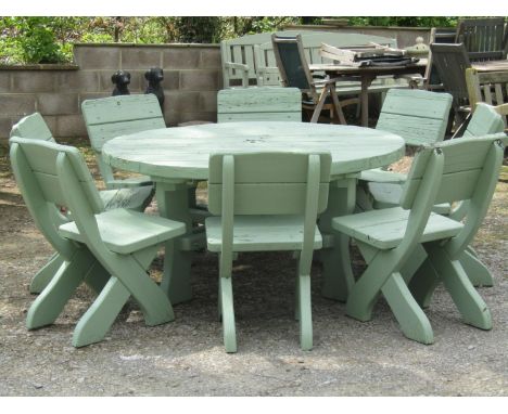 A substantial light green painted wooden garden table with circular boarded top 150 cm diameter, together with a set of eight