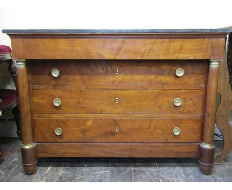 Early 19th century French Empire period walnut commode of four drawers with turned column supports, black marble top and furt
