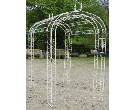 A painted and weathered decorative light tubular steel framed garden double rose arch with simple repeating S scroll detail, 