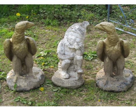 A pair of painted and weathered cast composition stone garden or pier ornaments in the form of eagles set on naturalistic bas