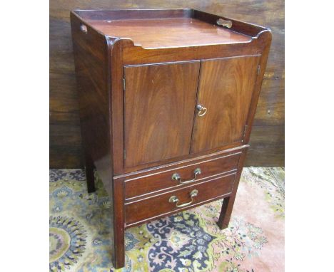 A Georgian mahogany tray top commode, the front elevation enclosed by a pair of panelled doors over the original stepped comm