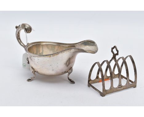A SILVER SAUCE BOAT AND TOAST RACK, the Georgian sauce boat of a plain polished design, scallop detailed rim, raised on three