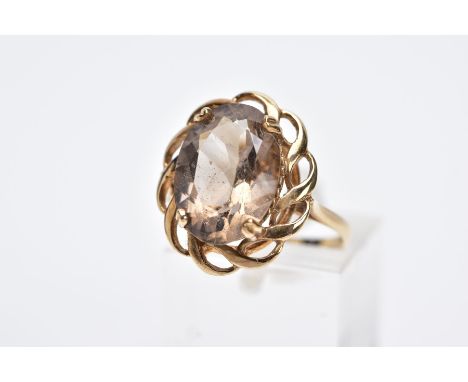 A 9CT GOLD SMOKY QUARTZ RING, designed with a claw set, oval cut smoky quartz within an openwork scallop surround, tapered sh