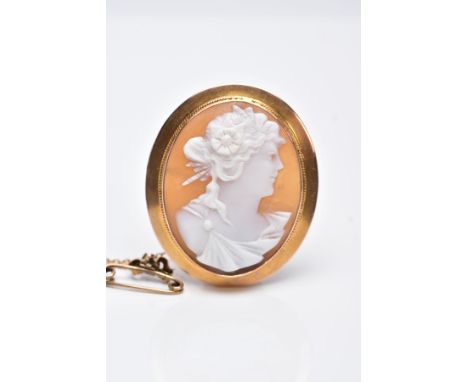 A YELLOW METAL CAMEO BROOCH, of an oval design depicting a lady in profile within a collet mount and a fine rope twist surrou