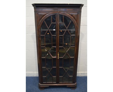 A GEORGIAN MAHOGANY ASTRAGAL GLAZED TWO DOOR FLOORSTANDING CORNER CUPBOARD, with four fixed shelves, on ogee bracket feet, wi