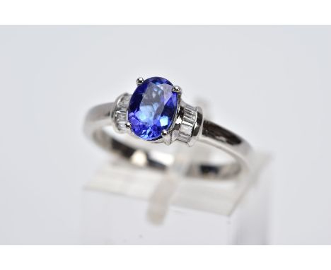 A TANZANITE AND DIAMOND PLATINUM RING, designed with a central claw set, oval cut tanzanite, stated weight 1.05cts, flanked w