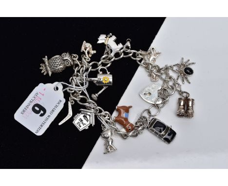 A WHITE METAL CHARM BRACELET, suspending twelve charms in forms such as a decorative enamel donkey stamped '925', a decorativ