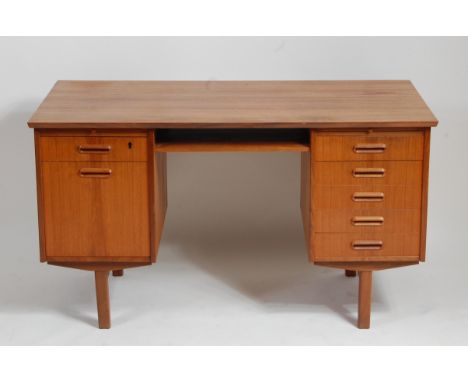 A 1960s Danish teak kneehole writing desk, having open upper central shelf, one pedestal with five drawers and the other with