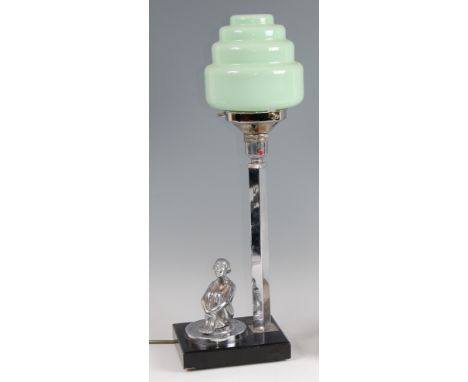 An Art Deco chrome and ebonised table lamp, having a green glass circular stepped shade mounted with a chrome figure of a sea